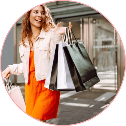 woman in orange dress carrying multiple shopping bags while walking outside
