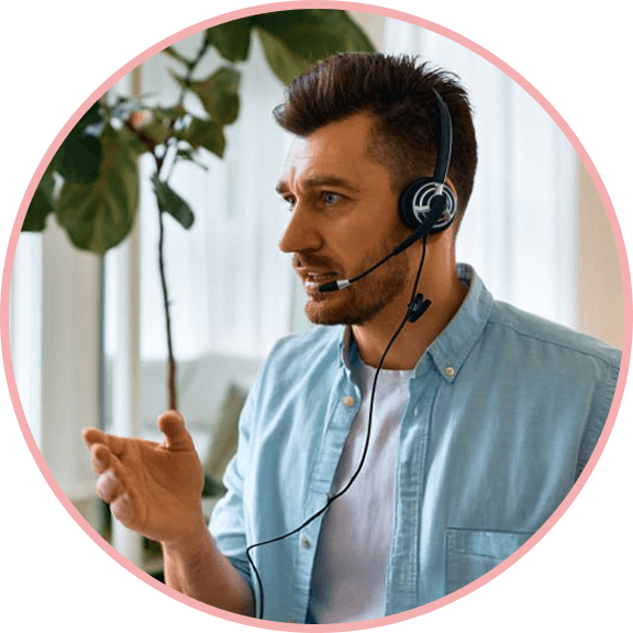 male customer service agent wearing a blue collared shirt and headset speaking on a video call