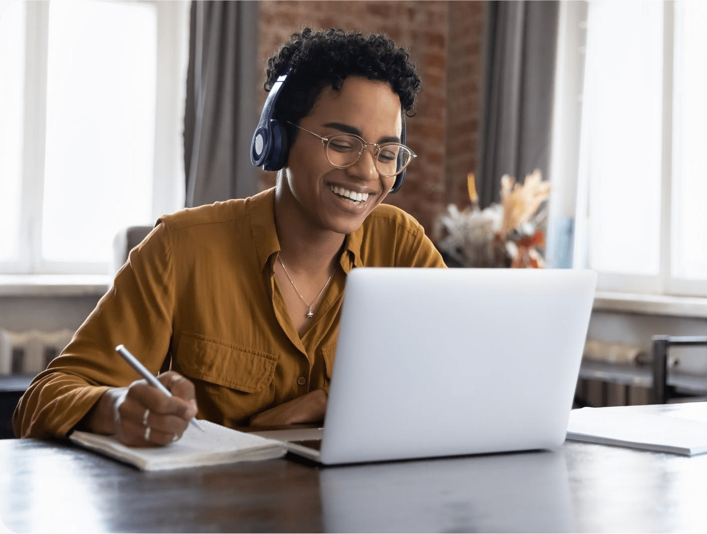 woman in headset smiling and speaking during video call at laptop